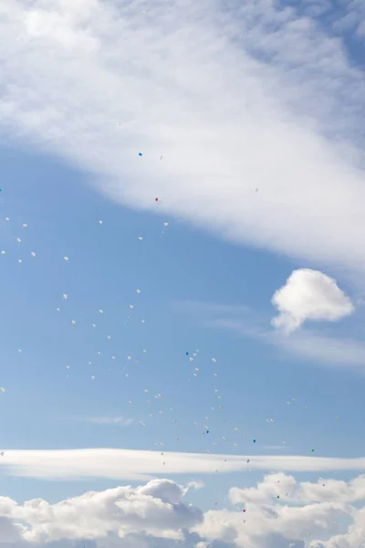 Πολύχρωμα μπαλόνια που πετούν στον ουρανό την άνοιξη μπλε με άσπρες σύννεφα — Φωτογραφία Αρχείου