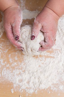 Kneading dough with flour on a wooden table at home