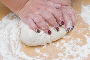 Kneading dough with flour on a wooden table at home