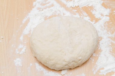 Prepared kneaded dough on a wooden table at home