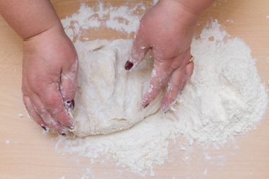 Kneading dough with flour on a wooden table at home