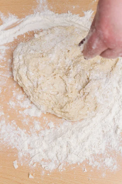 Teig mit Mehl zu Hause auf einem Holztisch kneten — Stockfoto