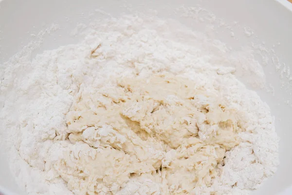 Готовить тесто в белой пластиковой миске дома — стоковое фото