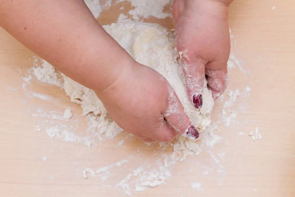 Teig mit Mehl zu Hause auf einem Holztisch kneten — Stockfoto