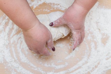 Kneading dough with flour on a wooden table at home