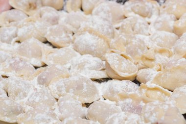 Hamur tatlısı, evde pişmiş, bir tabağa uzanmış, un serpiştirilmiş..