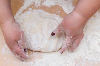 Kneading dough with flour on a wooden table at home