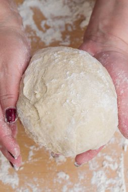 Kneading dough with flour on a wooden table at home