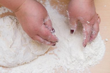 Kneading dough with flour on a wooden table at home