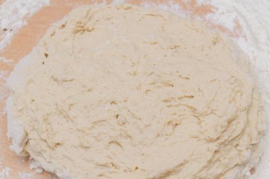 Kneading dough with flour on a wooden table at home