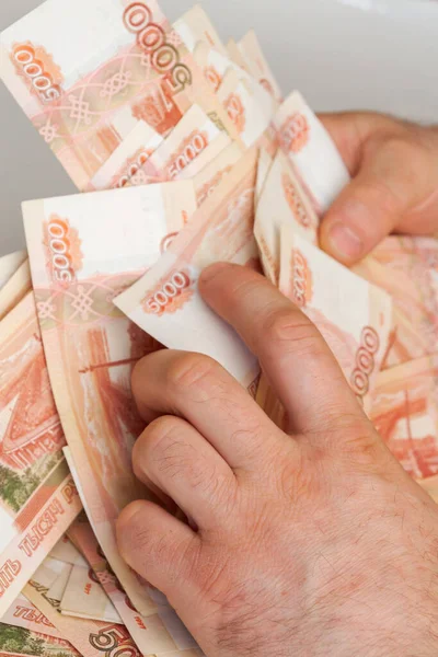 Beş bin rublelik Rus banknotlarıyla erkeklerin elinde büyük miktarda para var.