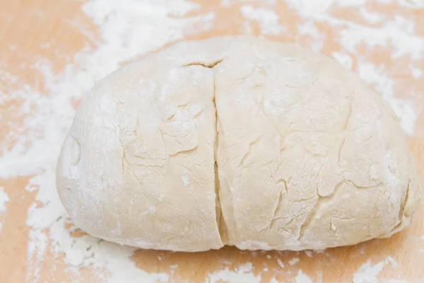 Prepared kneaded dough on a wooden table at home