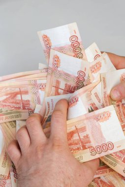 Beş bin rublelik Rus banknotlarıyla erkeklerin elinde büyük miktarda para var.