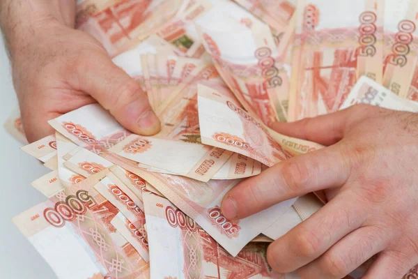 Men's hands hold a large amount of money with Russian banknotes of five thousand rubles