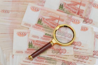 Altın saplı bir büyüteç Rus banknotlarının üzerine büyük miktarlarda 5.000 ruble konur.