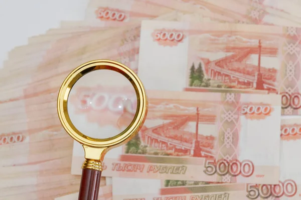 一个装有金柄的放大镜被放在5000卢布的俄罗斯纸币上 数量很大 — 图库照片