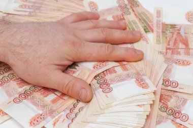Bir adamın eli beş bin rublelik banknotları sayar ve taşır.