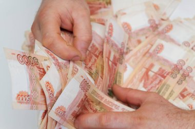 Beş bin rublelik Rus banknotlarıyla erkeklerin elinde büyük miktarda para var.