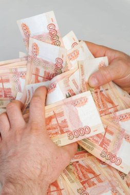 Beş bin rublelik Rus banknotlarıyla erkeklerin elinde büyük miktarda para var.