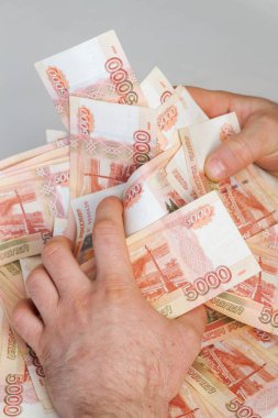 Beş bin rublelik Rus banknotlarıyla erkeklerin elinde büyük miktarda para var.