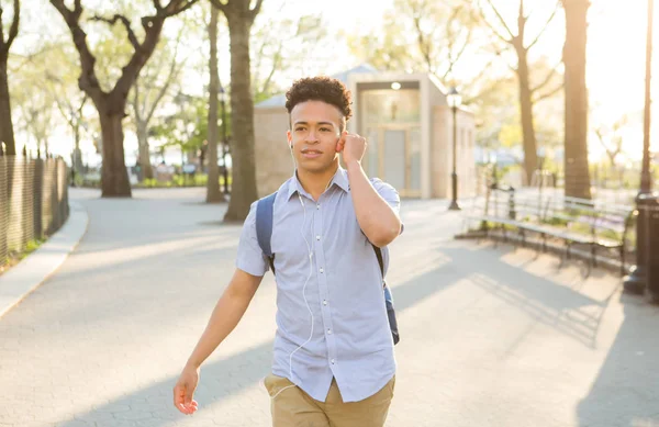 Hispanic student with curly hair walks on tree lined campus — Stock Photo, Image