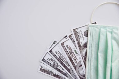 Tıbbi maske ve dolar parası, dünya koronavirüs salgını ve ekonomik kayıplar konsepti. Üst görünüm