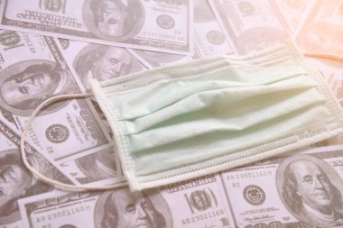 Tıbbi maske ve dolar parası, dünya koronavirüs salgını ve ekonomik kayıplar konsepti. Üst görünüm