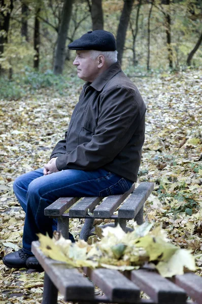 Elderly man sitting in the park on a bench — Stock Photo, Image