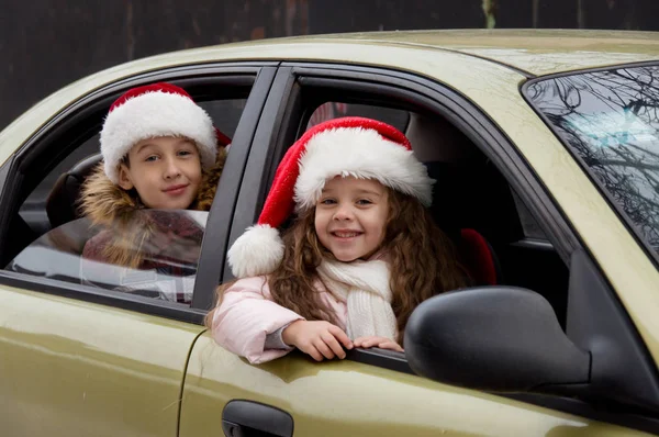 Dos niños en ropa de Navidad sentados en el coche Imágenes de stock libres de derechos