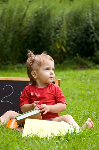 Petite fille dans le parc. apprendre à lire . — Photo