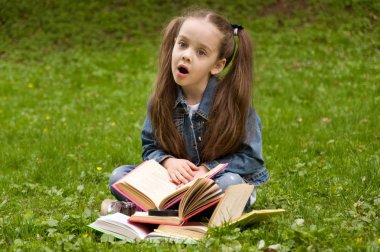 Liseli kızlar doğada bir kitap okuyor. Akıllı küçük Gözbebeğilerin
