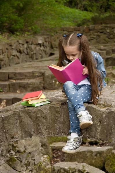 La colegiala está leyendo un libro en la naturaleza. Pequeño cachorro inteligente — Foto de Stock