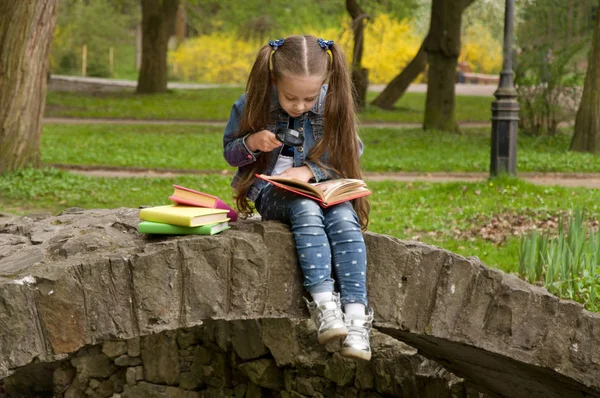 女の子は、虫眼鏡で本を読んでいます。スマート少し p — ストック写真