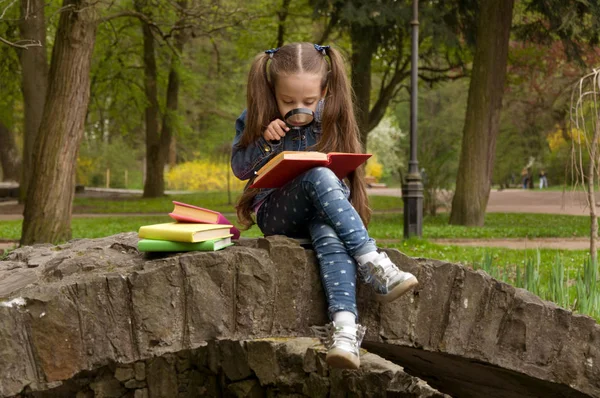女の子は、虫眼鏡で本を読んでいます。スマート少し p — ストック写真
