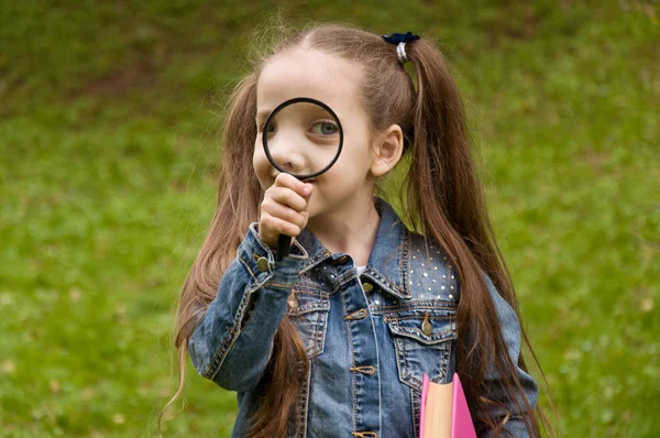 Little girl explores at nature through a magnifying glass — Stock Photo, Image