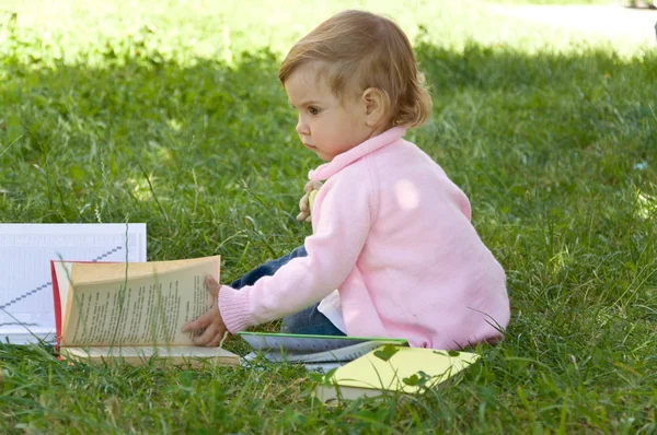 La petite écolière lit un livre dans la nature. Petite marionnette intelligente — Photo