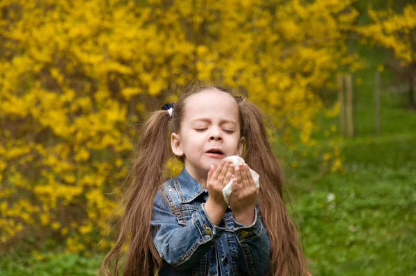 The girl has a runny nose. flowers pollen allergy. The girl is a — Stock Photo, Image