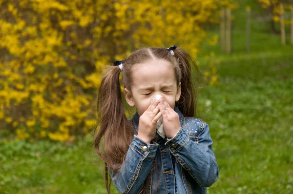 Flickan har en rinnande näsa. blommor pollenallergi. Flickan är en — Stockfoto