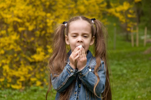 The girl has a runny nose. flowers pollen allergy. The girl is a — Stock Photo, Image