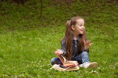 Liseli kızlar doğada bir kitap okuyor. Akıllı küçük Gözbebeğilerin