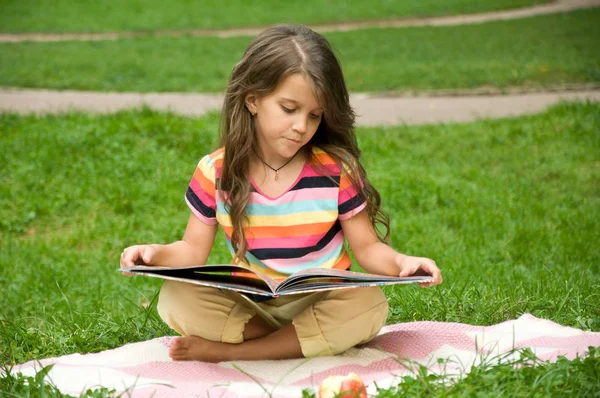 Malé školní děti číst knihu v přírodě. Inteligentní malou svěřenkyni — Stock fotografie