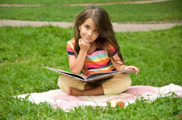 Malé školní děti číst knihu v přírodě. Inteligentní malou svěřenkyni — Stock fotografie