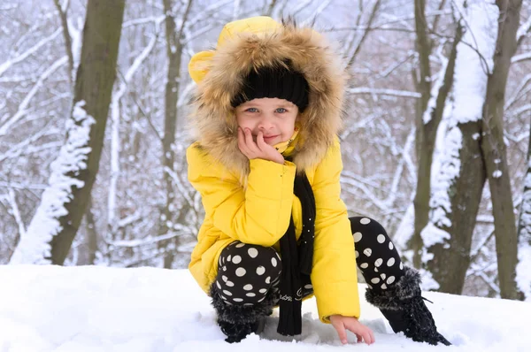 Liten flicka som leker i snön på vintern. — Stockfoto