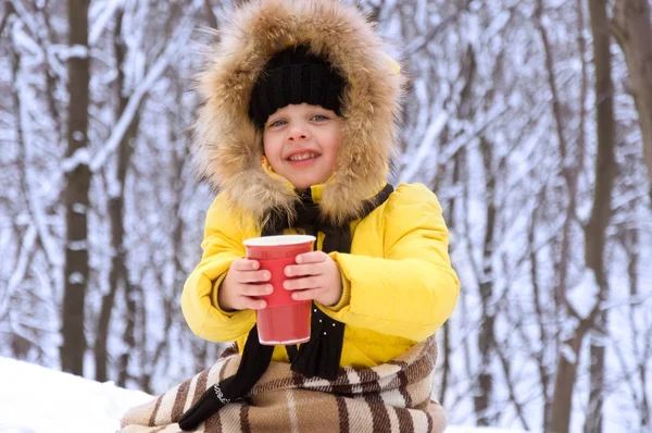 Kleines Mädchen im Winter auf der Straße und trinkt heißen Tee. — Stockfoto