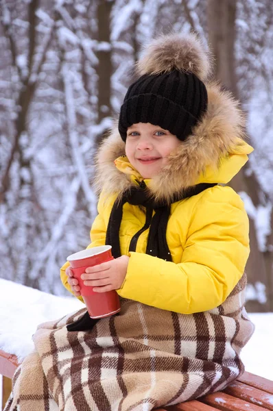 Kleines Mädchen im Winter auf der Straße und trinkt heißen Tee. — Stockfoto