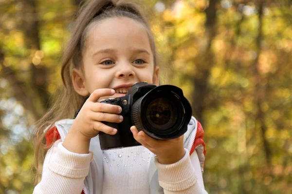 La niña sostiene una cámara y toma una foto. pasatiempo . — Foto de Stock