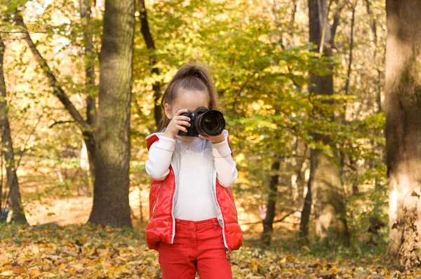 Little girl is holding a camera and taking a photo. hobby. — Stock Photo, Image