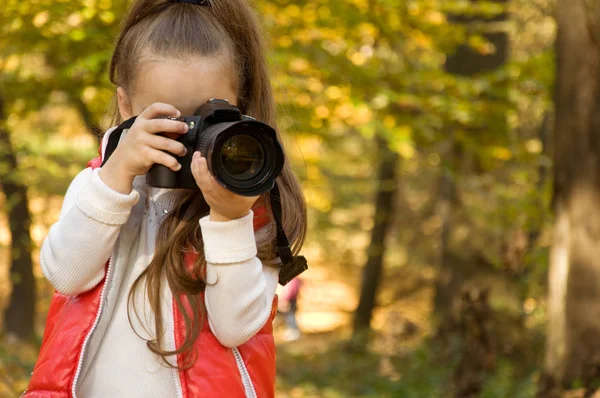 Malá holčička drží kameru a veselosti. koníček. — Stock fotografie