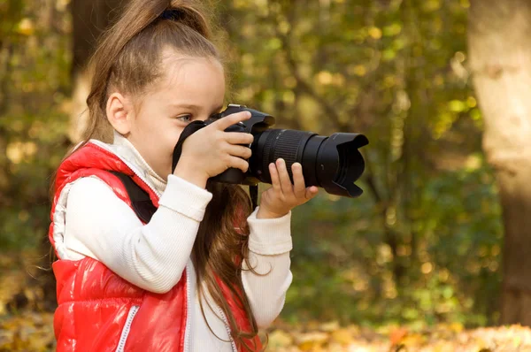 Kleines Mädchen hält eine Kamera und macht ein Foto. Hobby. — Stockfoto