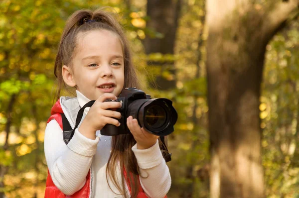 A menina está segurando uma câmera e tirando uma foto. hobby . — Fotografia de Stock